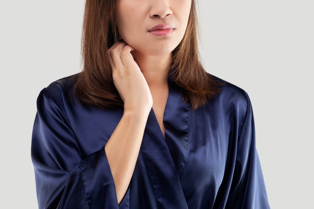 woman in a blue robe itching neck